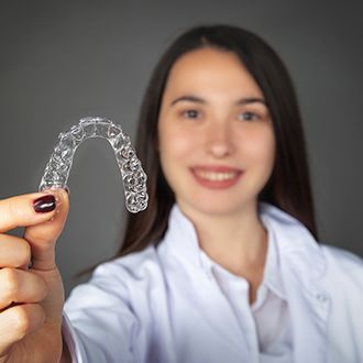 Smiling woman holding an Invisalign tray