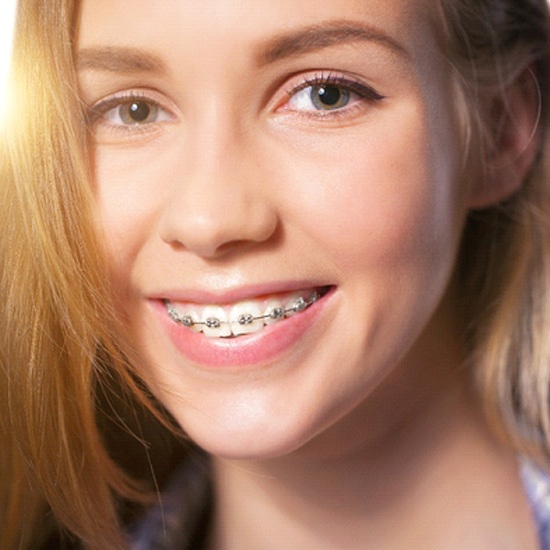 A young female showing off her metal braces after seeing an orthodontist in Dayville