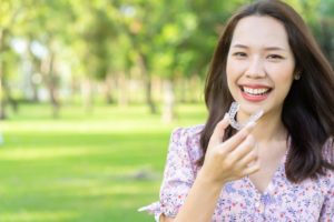 Woman smiles as she holds Invisalign in Dayville