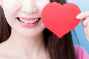 Closeup of smile with braces in Dayville and paper heart