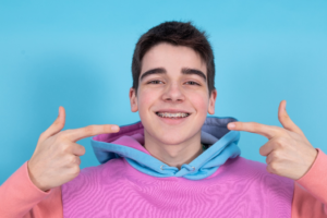a patient smiling and pointing to his braces