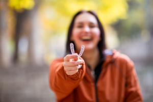a patient holding their Invisalign aligner and smiling